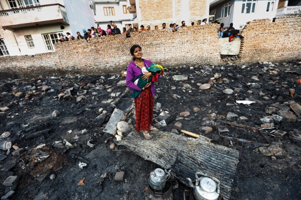 A mother holding her child cries in the remains of her burnt home after a fire at a slum in Kathmandu, Nepal.