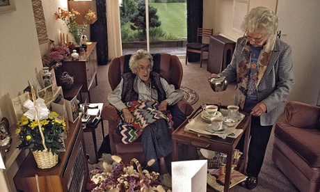 Home help serving up tea and cakes to elderly woman