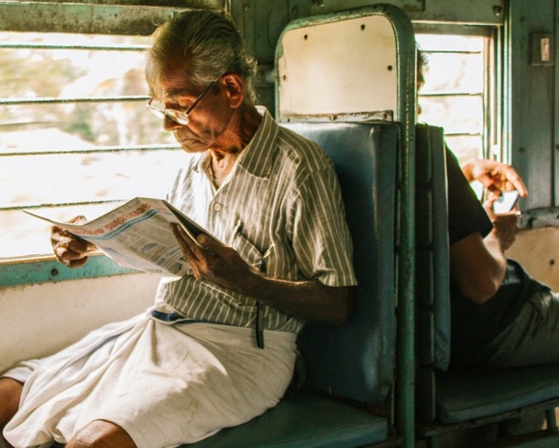 'A man reading on the train on the way to Kerela. In contrast, there is a young man behind him on his phone. A reflection on life and times.'