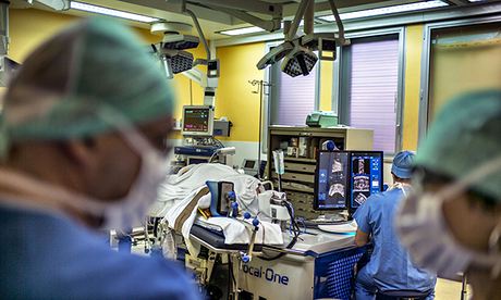 A surgeon sitting in front of screens of a Focal One device performs a prostate tumorectomy.