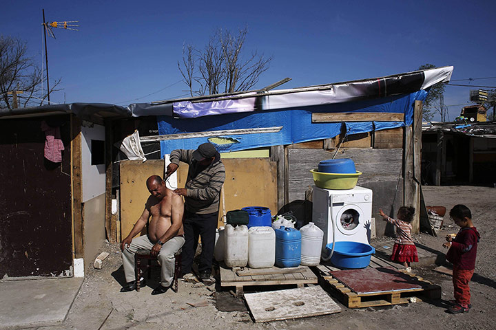 20 Photos: Children watch as a man has his hair shaved in the shanty town El Gallinero