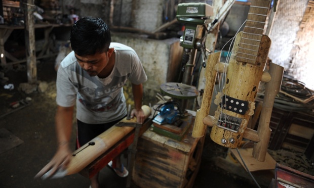 An artist works to make a bamboo lute and guitar in his workshop at Tanjung Wangi Village, Indonesia.