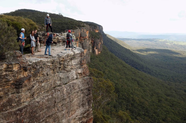 Prince William, leans over the cliff as Catherine, Duchess of Cambridge looks on while visiting the Narrow Neck Lookout and observe abseiling by the Mountain Youth Services group in the Blue Mountains in Katoomba, Australia.