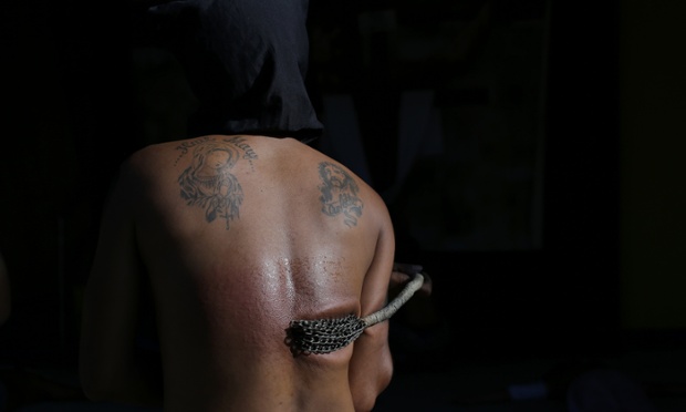 A hooded Filipino penitent flagellates himself as part of Maundy Thursday rituals to atone for sins in Mandaluyong, Philippines.