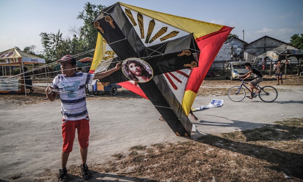 A Filipino prepares to fly a kite designed like a crucifix in Pampanga province, Philippines.