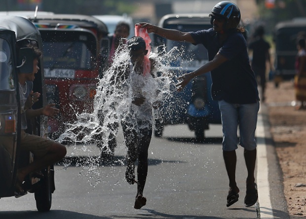 Homagama, Sri Lanka: A man pours water on a competitor during a road race as part of traditional festival games to celebrate Sinhala, the Hindu and Tamil new year.