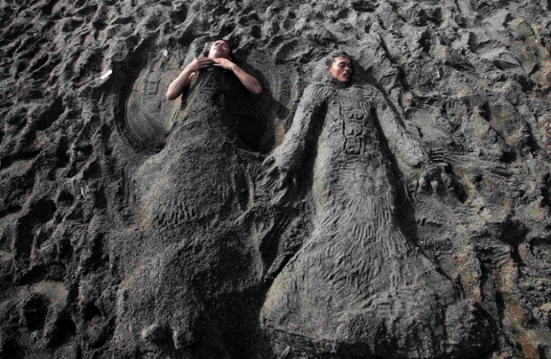 Cavite, Philippines: Two men are covered in sand at a beach as they celebrate Easter Sunday