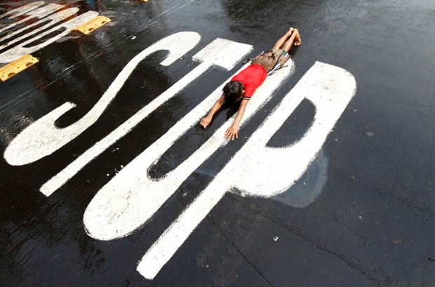 Kolkata, India: A boy crawls along on a road as he takes part in the Sheetala Puja ritual