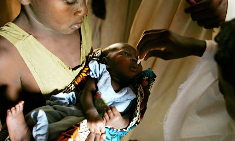 Nigerian field workers for the World Health Organisation inoculate a child with polio vaccine.