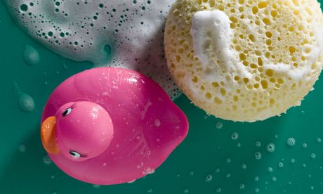 Rubber duck and sponge with soap foam, close-up