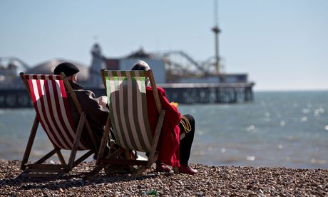 People sitting in chairs enjoying the sunshine on Brighton beach