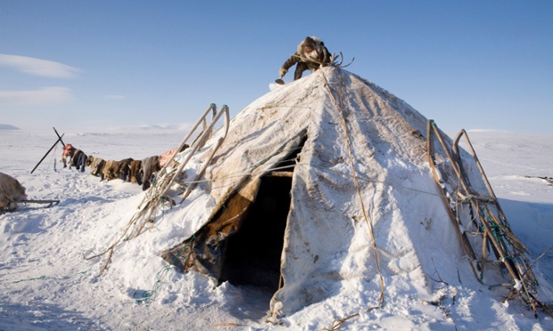 Natasha Nomro, a Chukchi woman, scraping snow from the top of her reindeer skin Yaranga at a herders' winter camp on the tundra. Chukotskiy Peninsula, Chukotka, Siberia, Russia