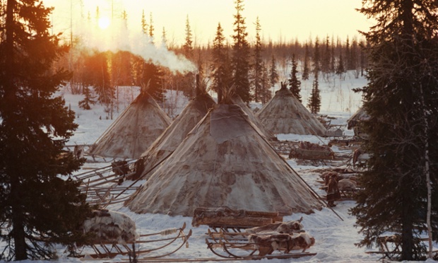 Sun rises behind reindeer skin tents at a winter camp of a group of Nenets herders. Yamal.