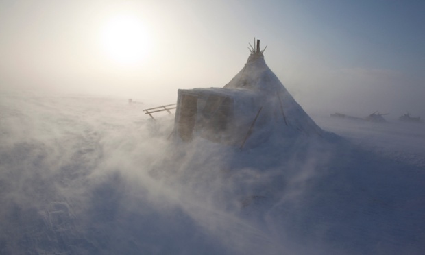 During a Spring storm, blowing snow swirls around a Nenets reindeer herders' winter camp on the tundra near Tambey. Yamal Peninsula, Western Siberia, Russia