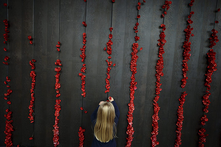 20 Photos: A girl places a poppy on the roll of honour at the Australian War Memorial