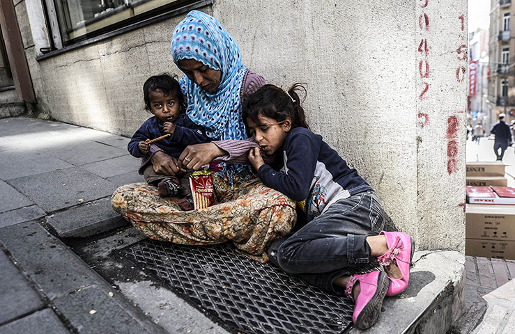 20 Photos: A Syrian woman sits with her children on a pavement in Istanbul