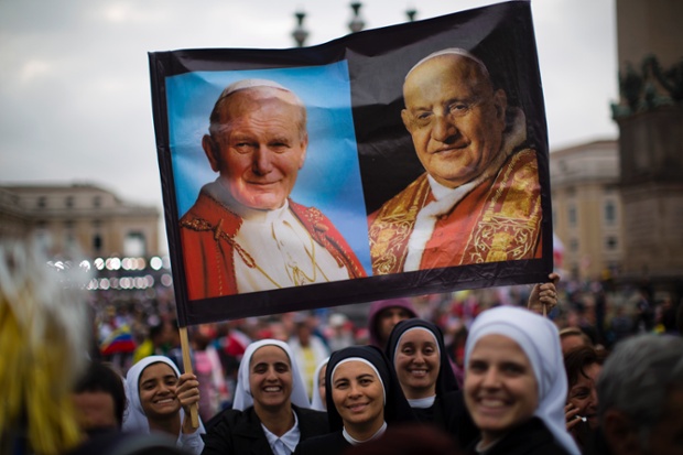 Nuns hold up a poster with portraits of Pope John Paul II, left, and John XXIII, in St Peter's Square.
