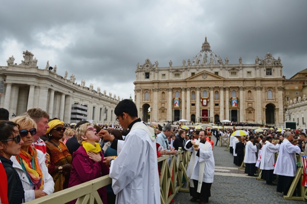 Priests give communion to pilgrims after the canonisation ceremony.