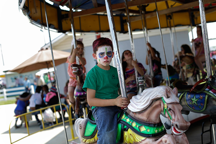 FTA: Angola Prison Rodeo: A boy with a painted face rides on a merry-go-round 