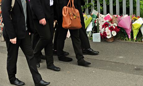 Schoolchildren walk past floral tributes to Anne Maguire at Corpus Christi Catholic college 