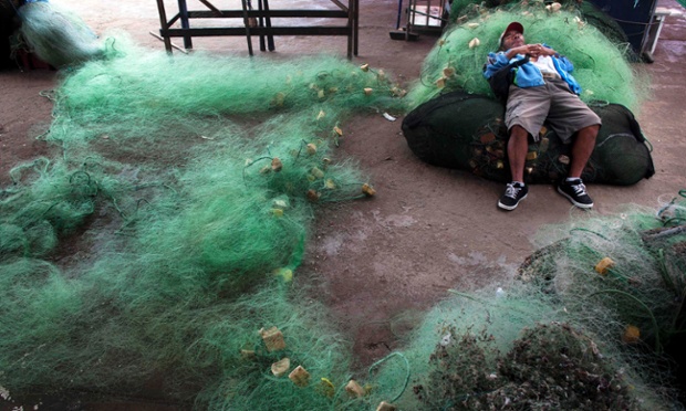 A fisherman naps on tangled fishing nets in Lima, Peru.