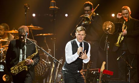 Gary Barlow fronts a nine-piece band on stage.