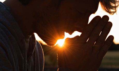 Man praying at sunset