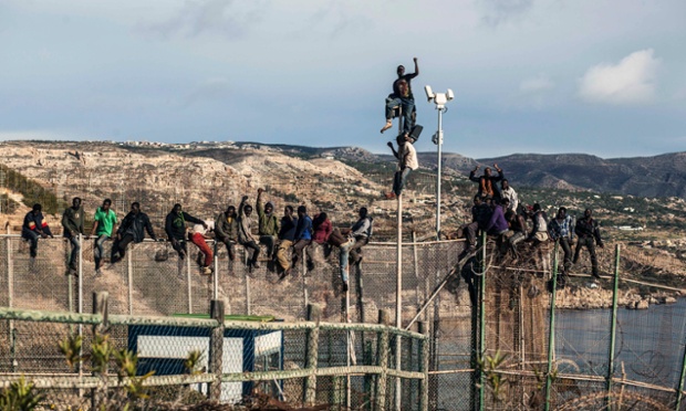 Would-be immigrants sit atop a boarder fence separating Morocco from the north African Spanish enclave of Melilla