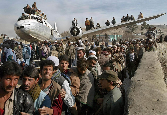 20 Photos: Afghan men next to a destroyed passenger plane in Kabul