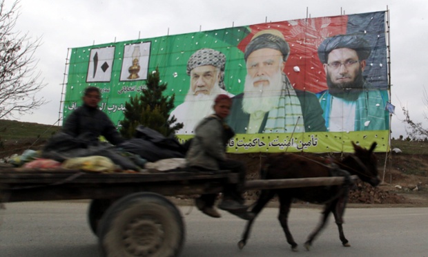 A donkey cart passes by electoral billboards of presidential candidate and former Islamist warlord Abdul Rasul Sayyaf displayed on the eve of Presidential elections in Kabul.