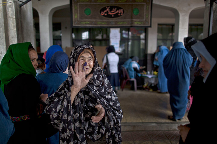 Afghan: An elderly woman shows another woman her inked finger 