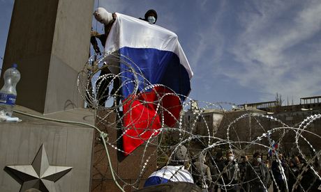 A masked man holds Russian flag above a barricade