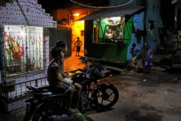 A family in their small slum residence, chatting and watching television at night, in the soon-to-be-destroyed Panditya Basti, on the outskirts of Kolkata.