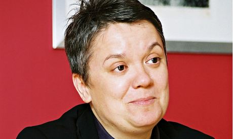 Portrait of Karon Monaghan, sitting at a desk hands resting on each other