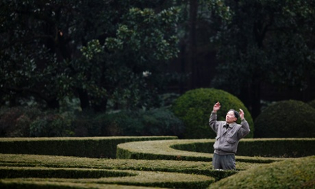 An elderly man exercises in a park downtown.