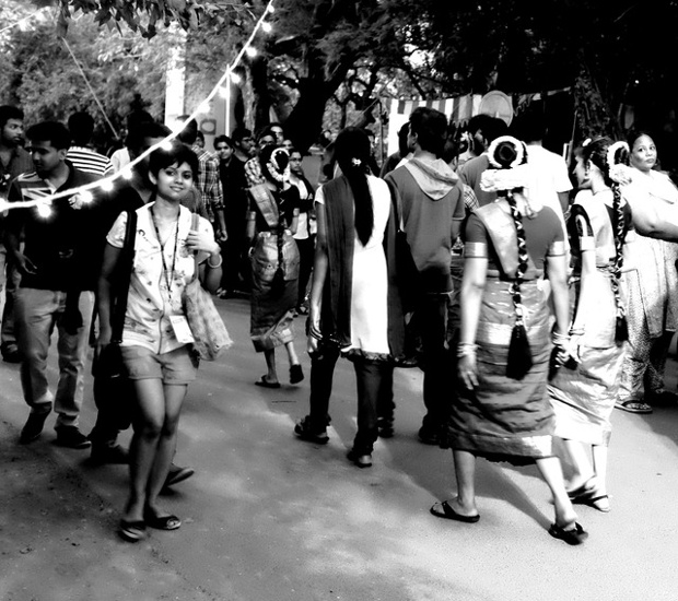'An image showing two sides of India (at least urban India): young women on their way to perform a traditional Indian dance along side a modern young woman. The coexistence is rather peaceful in most places and in most people as well.'