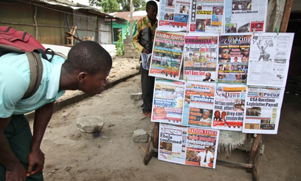 A Liberian student reads newpaper headlines on the Ebola epidemic, Monrovia, Liberia