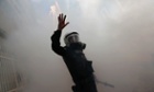 A riot police officer gestures amid tear gas during a May Day demonstration in Istanbul.