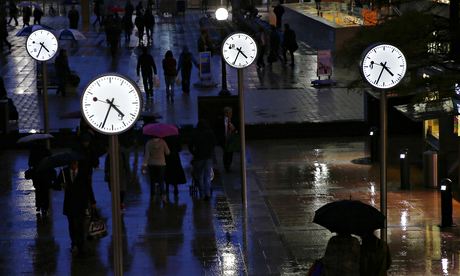 Workers walk in the rain at the Canary Wharf business district in London