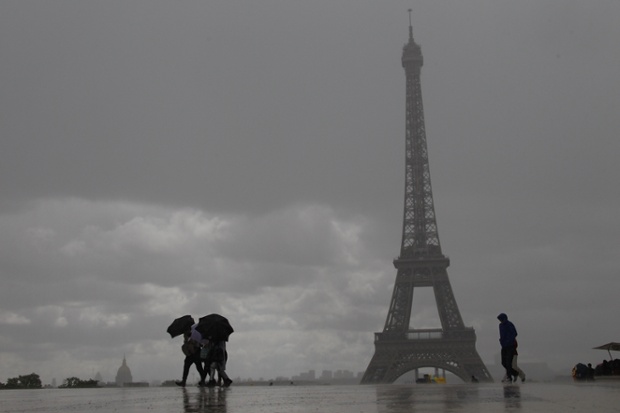 People walk in heavy rain near the Eiffel Tower, in Paris.