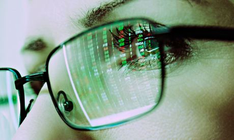 Female face with spectacles reflecting a computer screen display of stock market prices