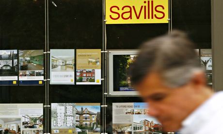 A pedestrian walks past a branch of Savills