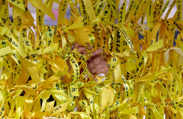 A woman ties yellow ribbons with messages for missing passengers aboard the sunken ferry boat Sewol in the water off the southern coast, in Seoul, South Korea.
