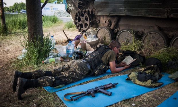 An Ukrainian soldier reads a book at a temporary camp near a checkpoint in Mariupol, Ukraine after President Putin ordered all troops stationed along the border with Ukraine to withdraw.