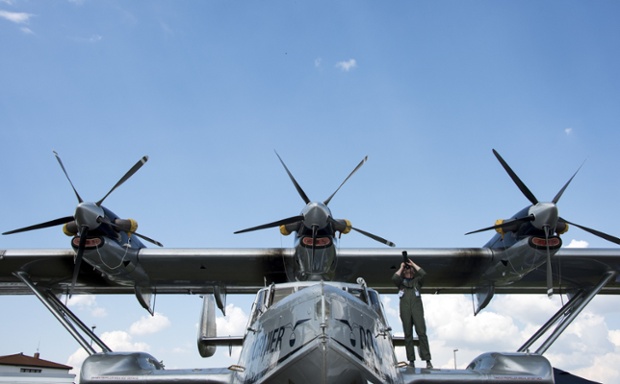 While a man takes a picture from the wing of a turboprop-powered amphibious aircraft, the Dornier Seastar.