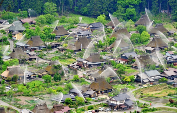 Το νερό ψεκάζεται πάνω αχυρένια στέγη αγροικίες κατά τη διάρκεια των εξαμηνιαίων ασκήσεις φωτιά στο Kayabuki no Sato, Κιότο, Ιαπωνία.