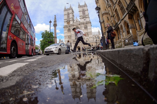 A leap of faith? An office worker jumps over a puddle near Westminster Abbey after a heavy rain storm in central London. 