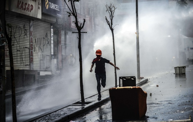 A protester runs away as Turkish riot police use water cannons to disperse protesters in Istanbul during a demonstration against the recent mine accident in Soma.