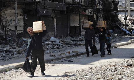 Palestinians from the besieged al-Yarmouk camp receive food aid from UNRWA, south of Damascus