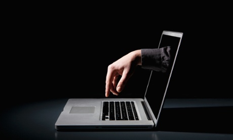 A hand reaching through a laptop to type on the keyboard